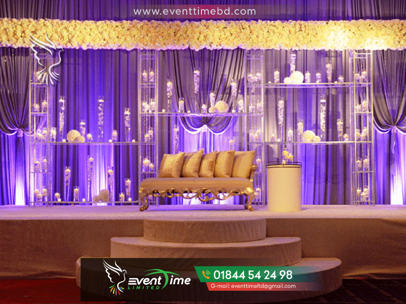 Wedding Planner BD – EVENT TIME LTD and Entertainment are one of the best wedding planners in Bangladesh.  In fact, Our Main offices are in Dhaka Bangladesh. From 2006 we started to doing wedding management company. Meanwhile, from our beginning, we have done more than 100 wedding event planning, wedding event budgeting, etc. We make all the wedding event management customize packages as per our client’s requirements and budgets. So, all of our clients were happy to get memorable events within their budget. Best Wedding Event Planners in Bangladesh The wedding ceremony follows the Gaye Holud traditions. The bride’s family arranges the wedding ceremony. The groom, along with his friends and family (Borjatri), traditionally arrives later in the evening. The groom is sent a car from the bride’s side. He rides inside it with two elder male relatives. One from the bride’s side and another from his own family. Called his Borkorta as well as the youngest male member of his family. Dressed as a groom Named his Neet bor, similar to the “best man” in western traditions). Event Time Bd Before leaving for the wedding venue groom is blessed by his Mother. He formally seeks her permission to begin a new life with his soon-to-be “better half”. At a Muslim wedding, the groom’s mother leaves along with the groom and takes him to the Bride’s house. However, in contrast to the Hindu ceremony. The groom’s mother presents the bride with jewellery and sarees. Then changes into her wedding saree and jewellery in Muslim ceremonies. Event Time Bd Top 10 Event Management Later, the groom and his father and the bride’s father meet to sign the official mahr contract. Ritually giving the Bride a set amount of money as her dowry. In a Muslim ceremony, the bride and groom are stated separately, Family and friends. Each bride and groom with a Huzur’ who asks both. They accept the other as their partners and if they say “Kabul” (means I get it). Then they sign the wedding document. Then seated next to each other and ask for the blessing of their family and God. Andbride’s side of the family, dance, take pictures, and talk with the guests. The following day (preferably before noon). the new couple leaves for the groom’s house that evening. This is known as the Bidaay goodbye or farewell ceremony. Best Wedding Event Planners When the bride is greeted by the groom in the morning. where he gifts the bride with essential accessories. A married woman. A sari and other auspicious things on a plate of silver. These items are given by the husband only and not by the in-laws of the bride. Nowadays they also use other metals like brass etc. This signifies that the groom would hence be taken care of. All the needs and requirements of his bride from that day onwards. Marriage, in our society, represents not only the sacred union of two individuals. Also the alliance of two families and extended relatives. Their level of involvement is so high that the bride/groom is usually chosen by the family. Even a few decades ago, the bride and groom only saw each other. On their wedding day for the first time. In metropolitan regions, this pattern has shifted. And the younger generation now has a more significant role in picking their life mate. After receiving all these items from her husband. The bride takes a blessing from her husband and begins the rituals of “Bou Bhaat”. Top 10 event management companies in Bangladesh, BD Event Management & Wedding Planners, Creative Wedding Planner & Event Management, Creative Wedding Planner & Event Management - Facebook, BD Event Management & Wedding Planners, Wedding Planners in Bangladesh, Shadi Mubarak Event Management & Wedding Planner BD, BD Event Management & Wedding Planners, BD Event Management: BGMEA CUP 2022, Grand Finale, Event management picture, wedding planner cost in Bangladesh, event management system